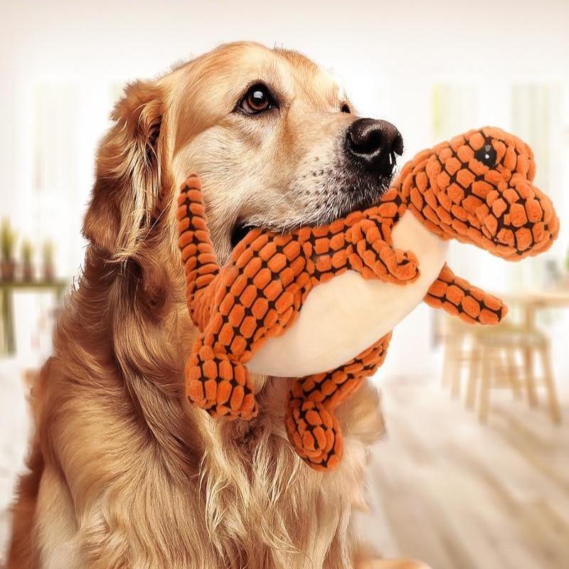 Golden Retriever playing with orange dinosaur plush dog toy